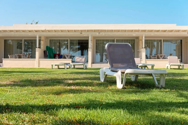 Pohodlné lehátko pro ideální odpočinek a opalování v salonku v hotelové zóně se zelenou trávou a palmami. Středozemní moře, Kypr. Ayia Napa. — Stock fotografie