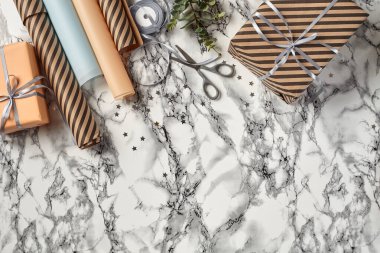 Farklı boyutlarda, çizgili ve sade, kahverengi ve pembe renkli hediye kutuları mermer arka planda gümüş kurdelelerle bağlanmış. Yakın çekim, kopyalama alanı, üst görünüm.