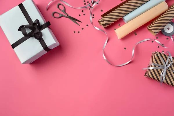 Diferentes tamaños, rayas y lisas, cajas de regalo de papel marrón y blanco unidas con cintas negras y plateadas en un fondo rosa. Cierre, espacio de copia, vista superior. — Foto de Stock