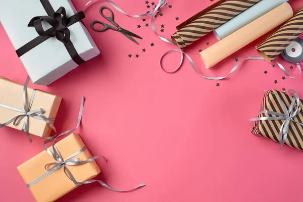 Diferentes tamaños, rayas y lisas, marrón, rosa y blanco cajas de regalo de papel atadas con cintas negras y plateadas en un fondo rosa. Cierre, espacio de copia, vista superior. —  Fotos de Stock