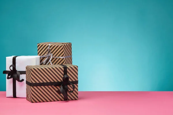 Olika storlekar, färgglada, randiga och vanligt papper presentförpackningar bundna med band och bågar på en rosa yta och blå bakgrund. Närbild, kopiera utrymme. — Stockfoto