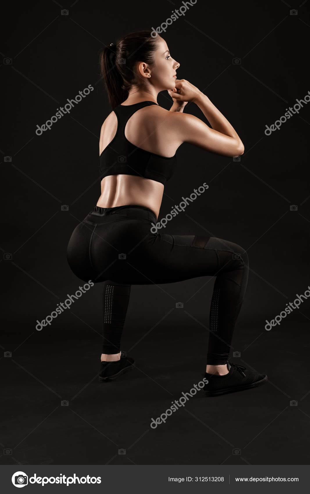 Brunette woman in black leggings, top and sneakers is posing