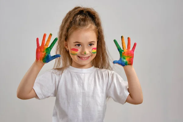 Klein meisje in wit t-shirt poseert geïsoleerd op wit en toont haar geschilderde handen, gezicht. Kunststudio. Close-up. — Stockfoto