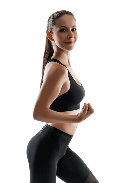 Brünette Frau in schwarzen Leggings, Top und Turnschuhen posiert isoliert auf weiß. Fitness, Fitness, gesundes Lebensstil-Konzept. — Stockfoto