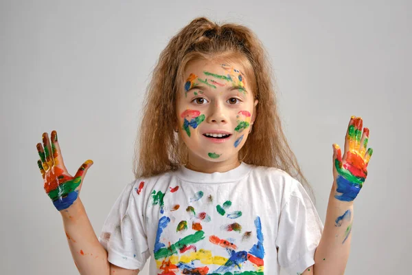 Klein meisje in wit t-shirt poseert staand geïsoleerd op wit en gebarentaal met haar geschilderd in verschillende kleuren palmen. Kunststudio. Close-up. — Stockfoto