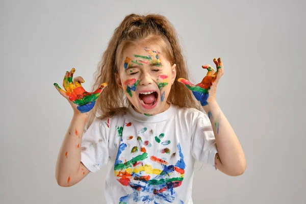 Pequeña chica con camiseta blanca está posando aislada sobre blanco y gesticulando con ella pintada en diferentes colores palmas. Estudio de arte. Cierre. —  Fotos de Stock