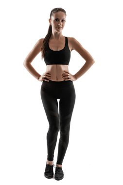 Siyah taytlı esmer kadın, üst ve spor ayakkabılı, beyaz üzerinde yalnız poz veriyor. Fitness, spor salonu, sağlıklı yaşam tarzı konsepti. Tam uzunluk.