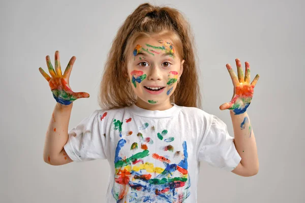 Klein meisje in wit t-shirt poseert staand geïsoleerd op wit en gebarentaal met haar geschilderd in verschillende kleuren palmen. Kunststudio. Close-up. — Stockfoto