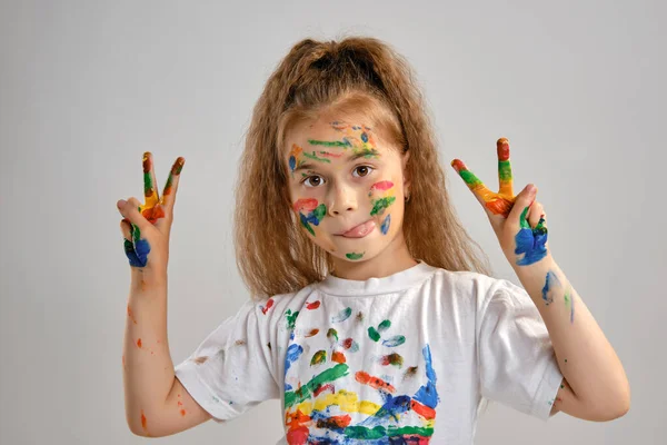 Klein meisje in wit t-shirt poseert staand geïsoleerd op wit en gebarentaal met haar geschilderd in verschillende kleuren palmen. Kunststudio. Close-up. — Stockfoto