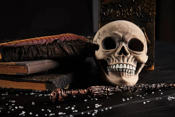 Modelo realista de um crânio humano com dentes em uma mesa escura de madeira, fundo preto. Ciência médica ou conceito de horror Halloween. Close-up shot. — Fotografia de Stock