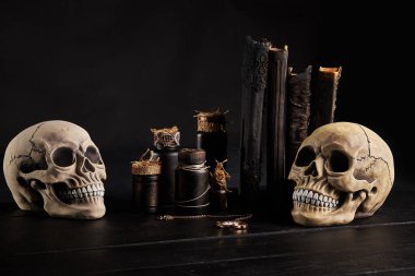 Realistic model of a human skull with teeth on a wooden dark table, black background. Medical science or Halloween horror concept. Close-up shot. clipart