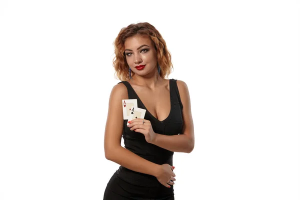 Ginger dívka v černých šatech je pózování drží dvě hrací karty v rukou stojí izolované na bílém pozadí. Kasino, poker. Detailní záběr. — Stock fotografie