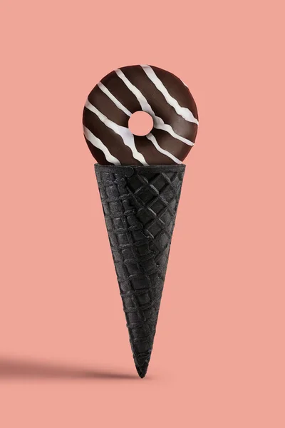 Donut de chocolate com cobertura branca em cone de wafer preto doce sobre fundo rosa. Alimentos, guloseimas e nutrição insalubre. Fechar, espaço de cópia — Fotografia de Stock
