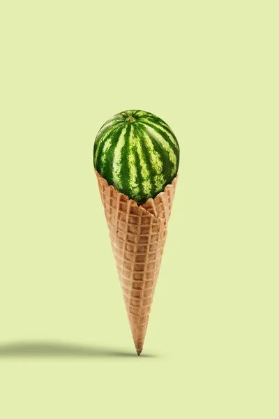 Green watermelon in sweet wafer cone on yellow background. Healthy nutrition, food, seasonal harvest of berries and fruits. Close up, copy space — Stock Photo, Image