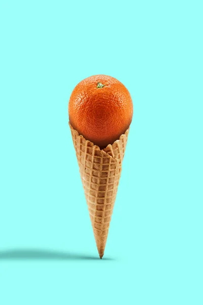 Naranja maduro en cono de oblea dulce sobre fondo turquesa. Nutrición saludable, comida y cosecha estacional de frutas. Cerrar, copiar espacio — Foto de Stock