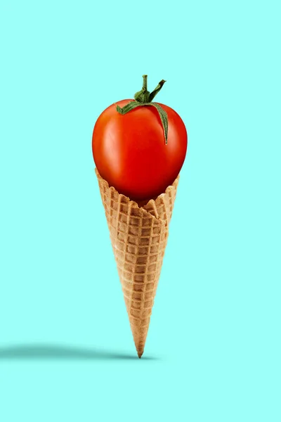 Tomate rojo maduro en un cono de gofre sobre fondo turquesa. Nutrición saludable, cosecha de verduras de temporada. Cerrar, copiar espacio — Foto de Stock