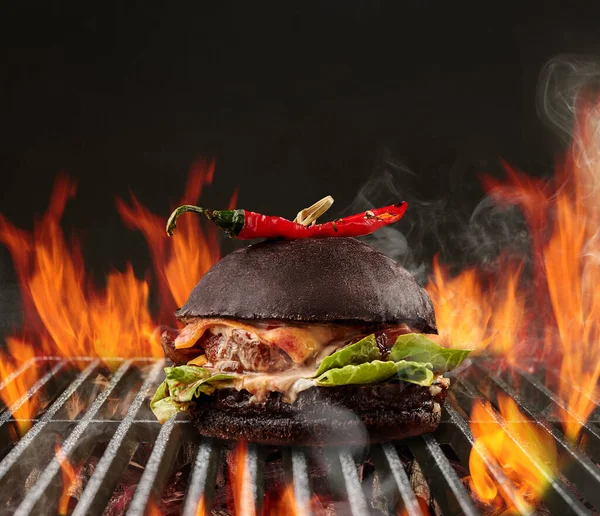 Hamburger au bœuf, laitue, fromage et poivron rouge rôti sur barbecue d'été portable en métal avec feu flamboyant et charbon de bois de braise. Gros plan — Photo