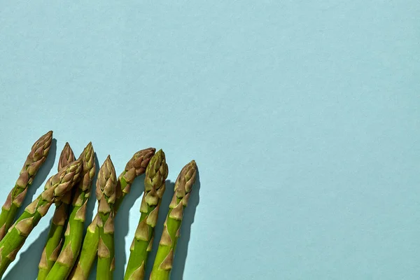 绿色生芦笋在蓝色背景上长出长矛.健康食品的概念和春季蔬菜的收成.关闭，复制空间 — 图库照片