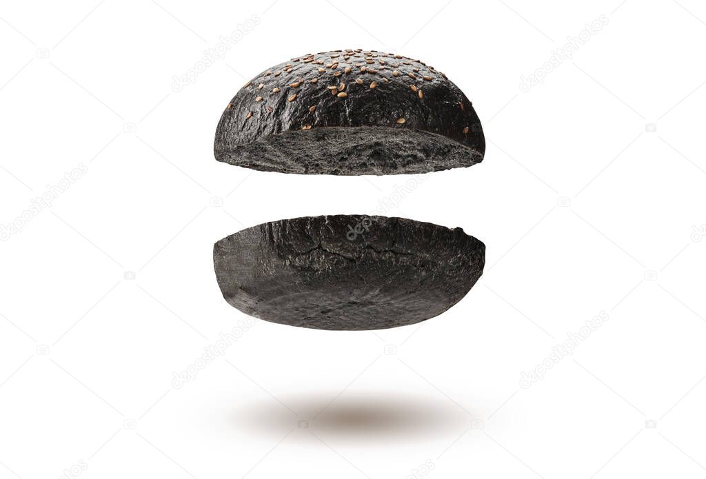 Flying, baked or grilled, cut in half black burger bun with sesame seeds isolated on white background. Cooking, fast food. Close-up, copy space