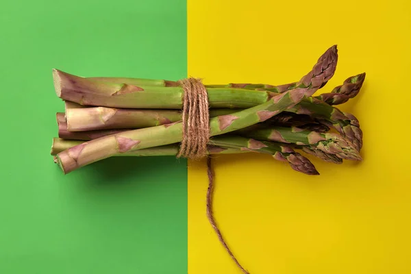 成熟的绿色芦笋串串在一起，用黄麻线绑在色彩艳丽的背景上。健康的营养，季节性蔬菜。关闭，复制空间 — 图库照片