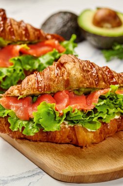 Taze yapılmış kruvasan sandviçleri füme somon, kremalı avokado ve kıtır marullarla dolu.
