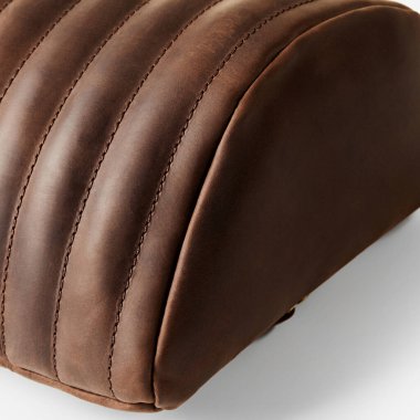 Dikey dikiş detaylarıyla kahverengi deri yastık, kaliteli işçiliği ve lüks tasarımı vurguluyor.