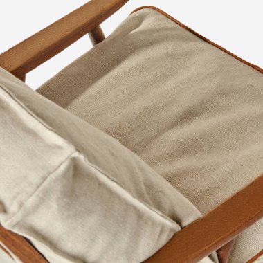 Modern koltuk rahat bej döşeme ve sağlam ahşap çerçeve sergiliyor. Rahat ve davetkar bir atmosfer yaratmak için mükemmel.