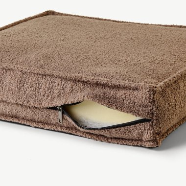 Kahverengi bir yastık kılıfının kapağı hafifçe açılmış, köpük ekleme ve fermuar kapağını ortaya çıkarmış.