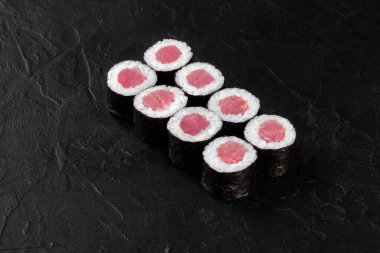 Taze yapılmış maguro hosomaki suşi dürümleri, ton balığı dolgusu içerir, koyu bir arka planda güzelce düzenlenir.