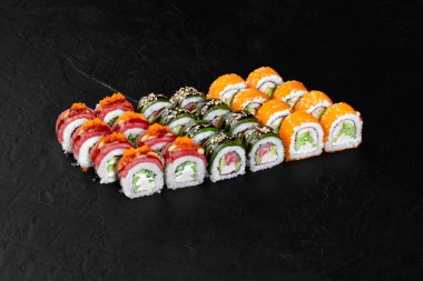 Farklı malzemeler ve dolgularla çeşitli suşi ruloları, renkli ve çekici bir sunum oluşturur.