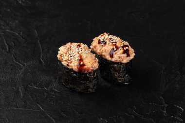 Baharatlı ton balığı, susam tohumu ve siyah arka planda unagi soslu Gunkan maki suşisi.