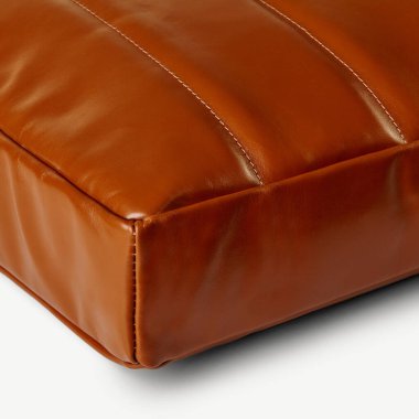 Kahverengi deri yastığın köşesindeki dikişlerin yakın çekimi, işçilik ve malzeme.