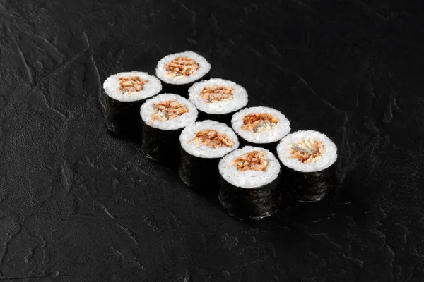 İçinde yılan balığı ve krem peynir bulunan siyah bir sayfada sekiz hosomaki.