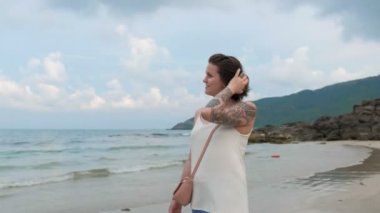 Güzel bir gülümseyen kadın tarafından okyanus kıyısında yürüyüş ve saçları ile oynamak