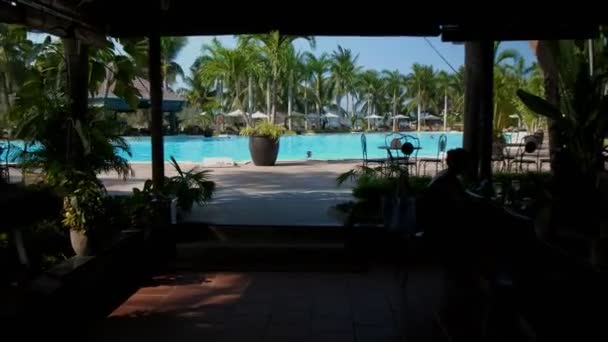 Обзор бассейна в жаркий летний день с пальмами и горами на заднем плане — стоковое видео