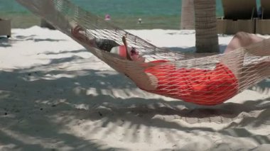 Kırmızı yalan ve hamakta sallanan bir genç gülümseyen kadın
