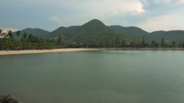 Palmiye ağaçları ve backgrond Dağları ile okyanus kıyısında Ttropical yağmur