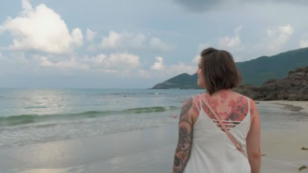 カメラに笑顔するビーチの上を歩く幸せな女。ステディカム撮影 — ストック動画