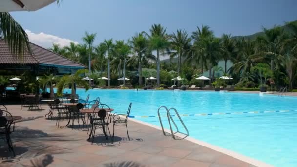 Piscina en día soleado Hotel de vacaciones con paraguas, palmeras, Resort. Contexto — Vídeo de stock