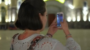 Bir close-up fotoğraf onun smartphone ile bir eğlence parkında akşam çekmek güzel bir genç kadın