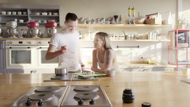 Um feliz casal europeu sorrindo está cozinhando e degustando sopa na cozinha — Vídeo de Stock