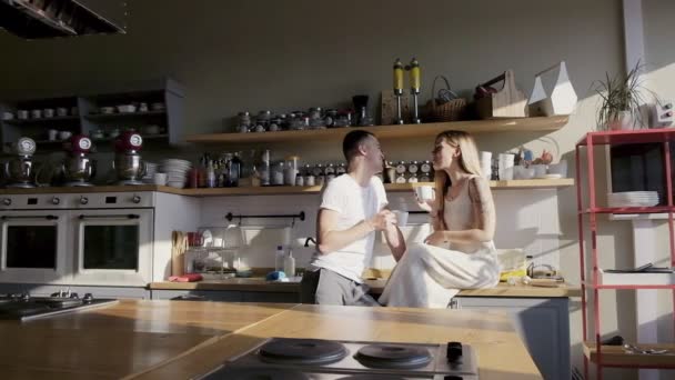 Красива європейська пара весело розмовляє і фліртує на кухні, повній сонячних спалахів — стокове відео