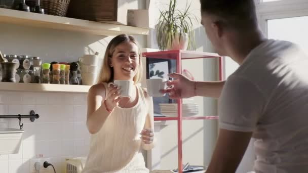 Una pareja cariñosa está disfrutando de la mañana soleada, tazas y sonriendo — Vídeos de Stock