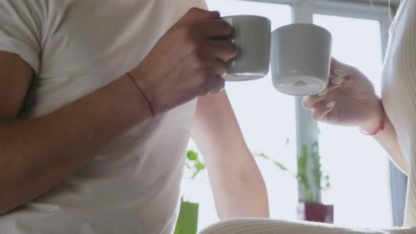 Le mani tengono due tazze bianche ai raggi del sole in cucina — Video Stock