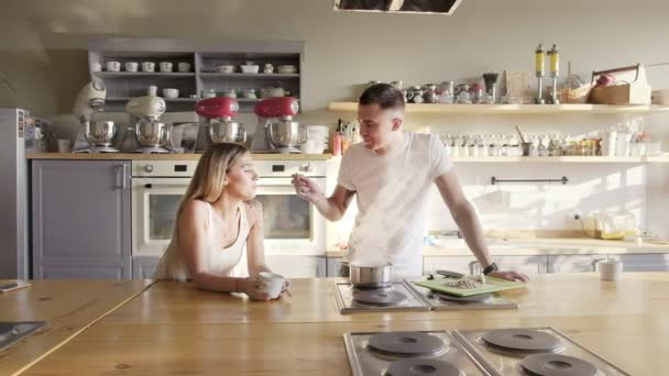 Счастливая европейская пара готовит и пробует суп на кухне — стоковое видео