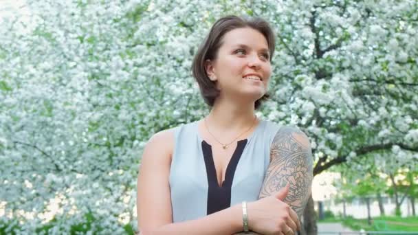 Young pretty tattoed girl is enjoying in apple tree blooming blossom — Stock Video