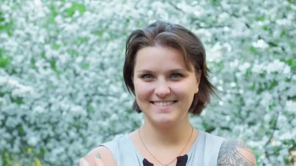 Portrét mladé hezké tattoed dívka se těší v strom kvetoucí jabloň — Stock video