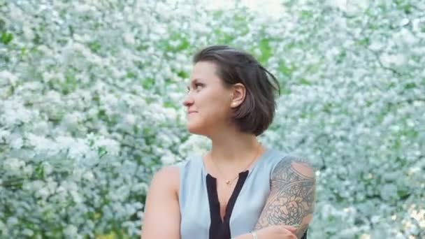 Young pretty tattoed girl is enjoying in apple tree blooming blossom — Stock Video