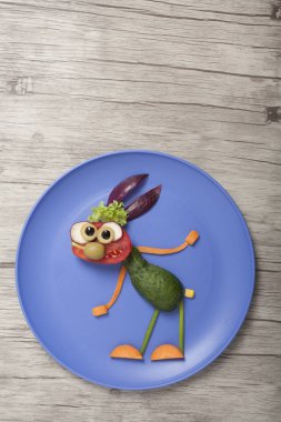 Mavi tabak ve ahşap tahta üzerine yapılan sebze tavşan