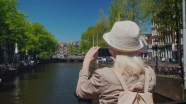Bir kadın turist şapka ve bir sırt çantası ile Amsterdam'da kanalı'nın güzel bir manzara resimleri. Hollanda ve Avrupa kavramı turizm